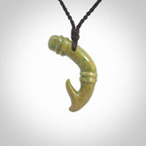 This photo shows a beautiful flower jade bamboo hook suspended from a hand plaited brown cord. The bamboo hook was carved for us by Jen Hung who is a master jade carver from New Zealand.